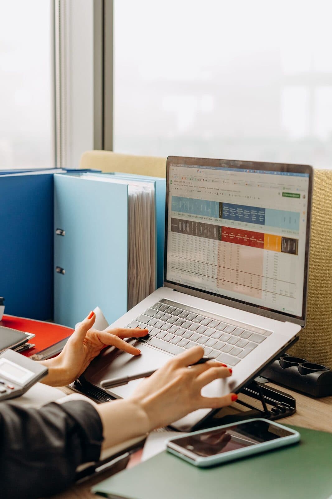 Hands on a laptop showing a rate spreadsheet beside ring binders