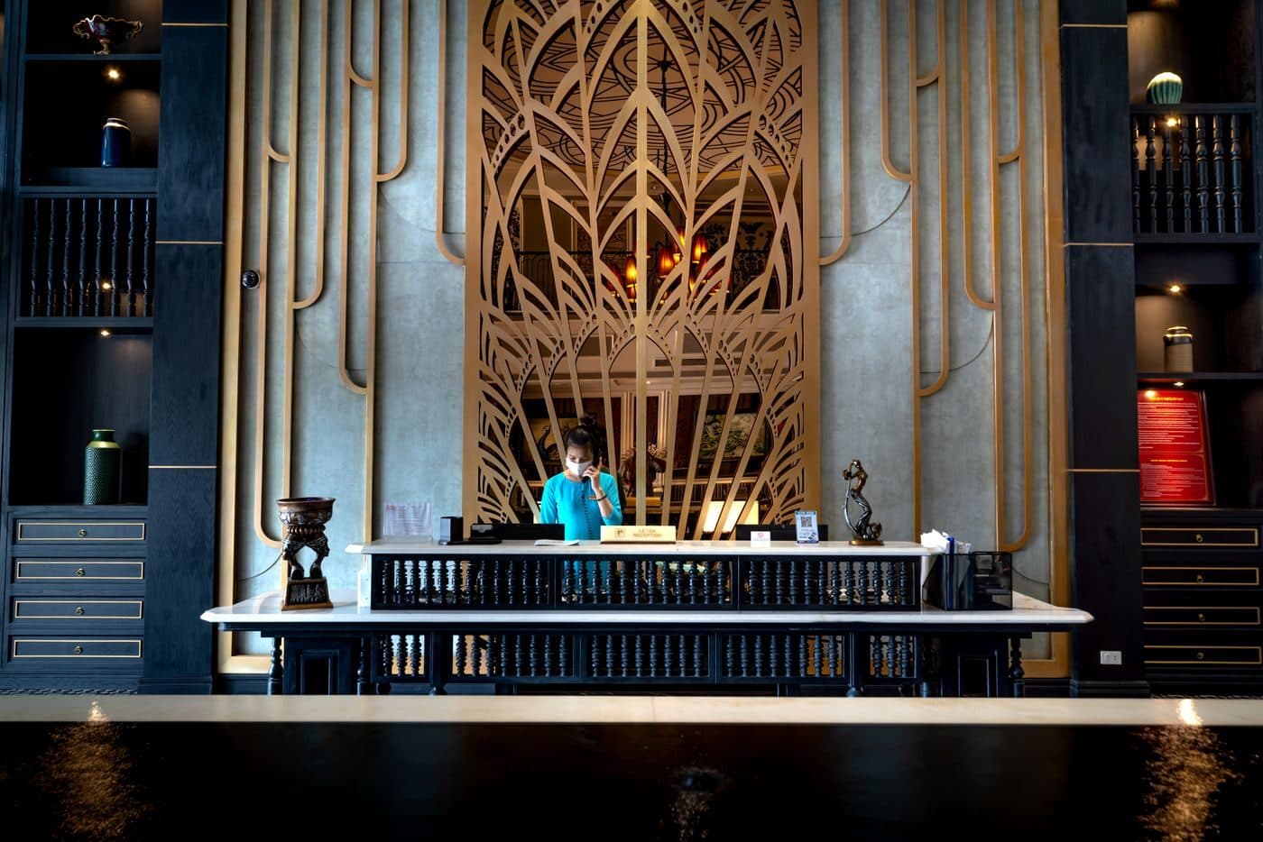 A receptionist behind the front desk of a hotel lobby at night