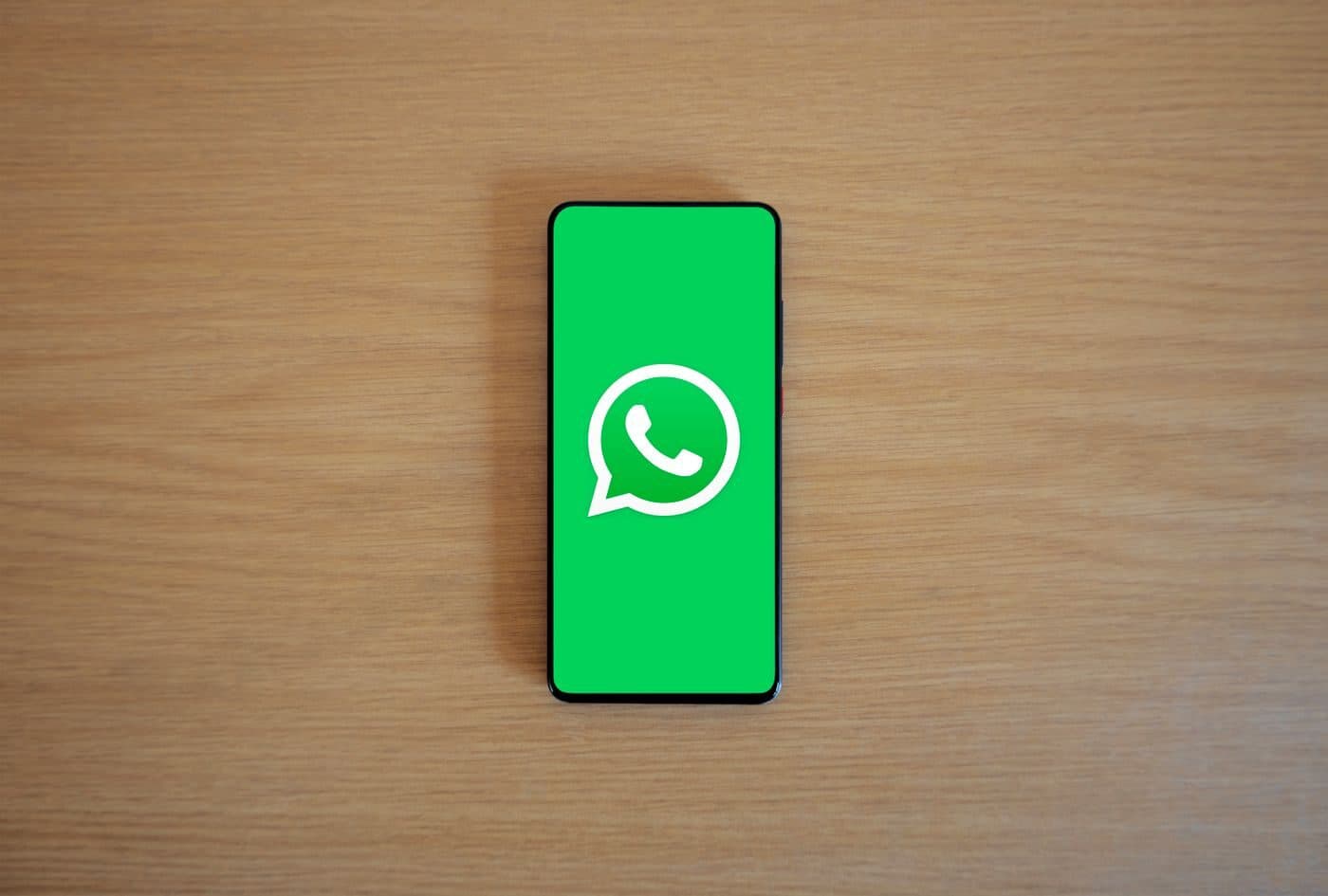 A smartphone on a desk showing the WhatsApp logo