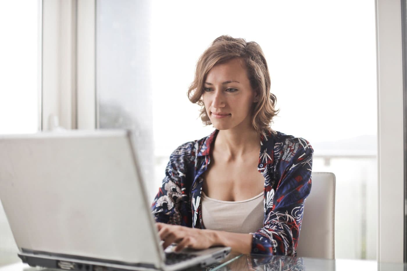 Someone working at a laptop beside a bright window