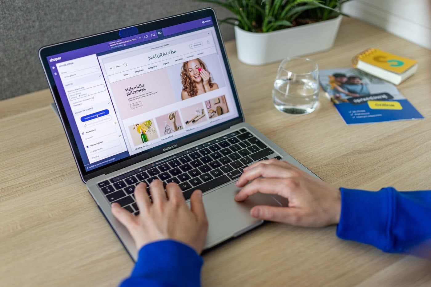 Hands typing on a laptop showing a website