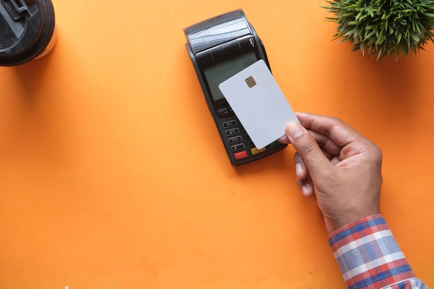 A hand tapping a bank card on a payment terminal