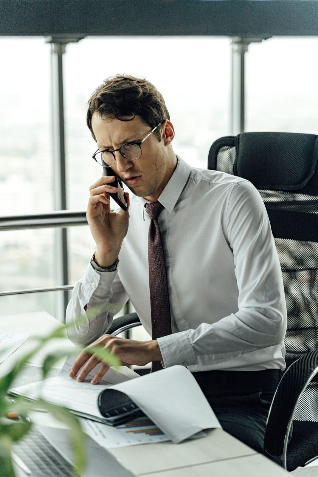Someone on a phone call while reviewing documents at a desk