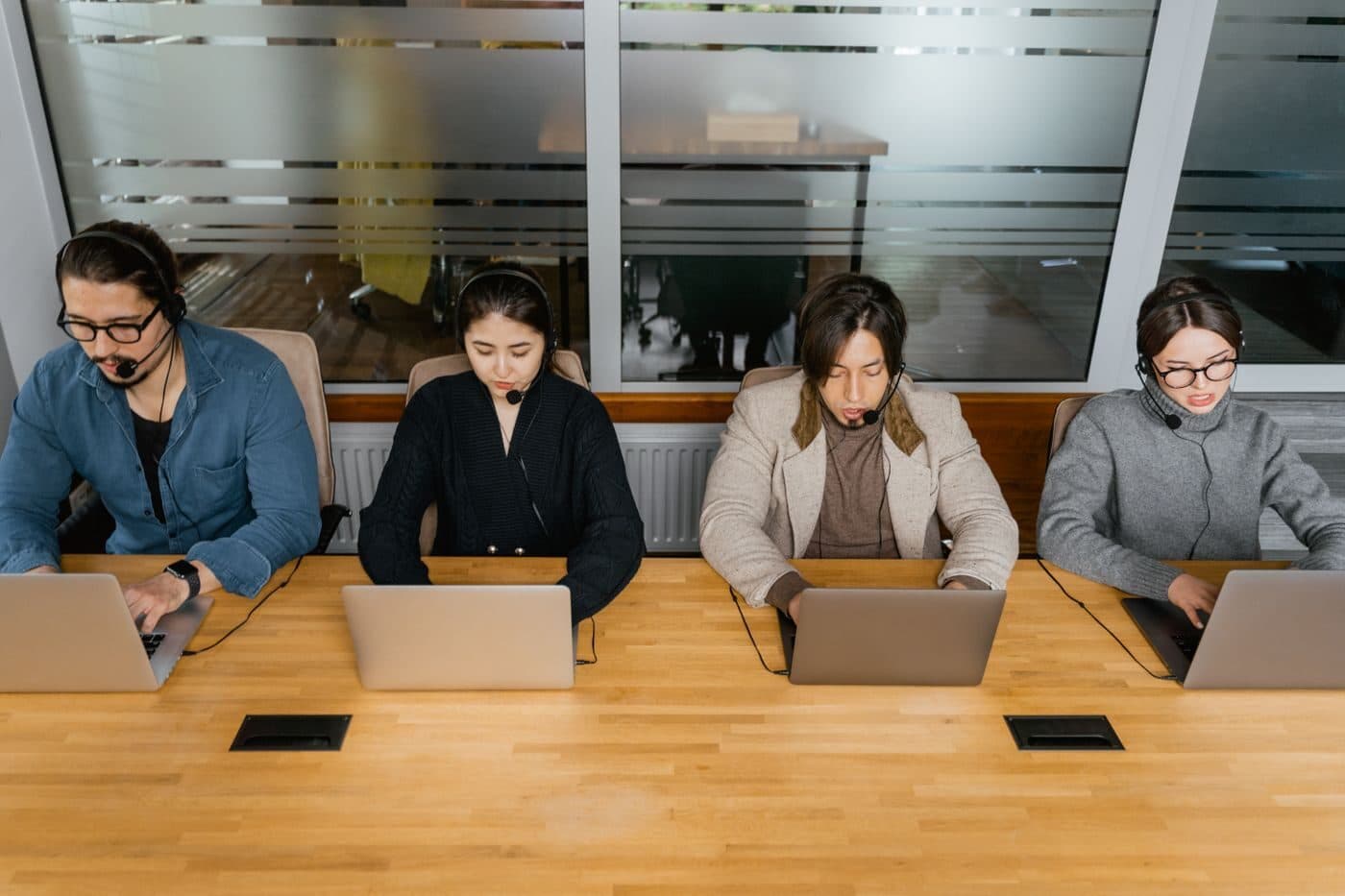 A team working side by side on laptops around an office table