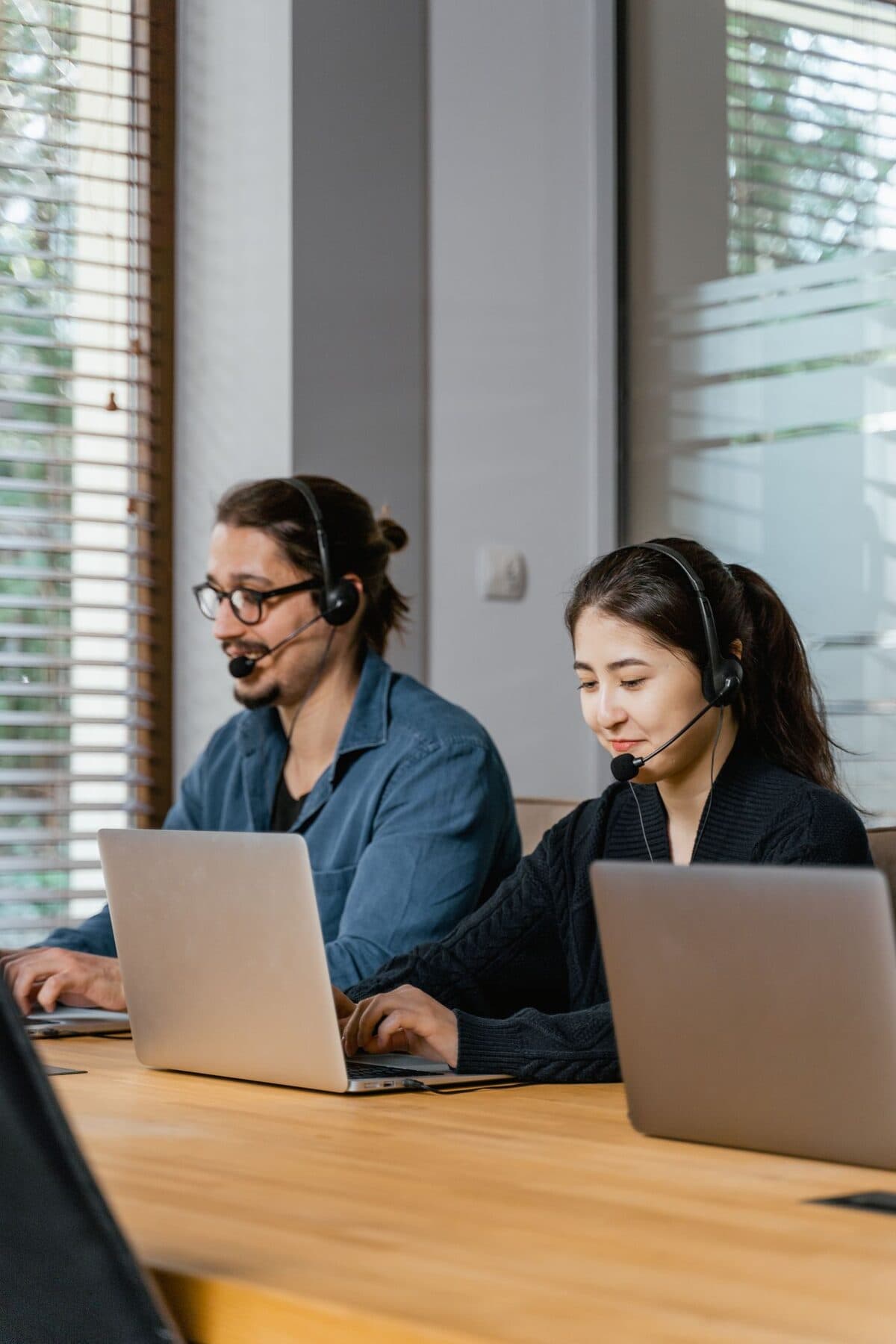 Two agents working with laptops and headsets