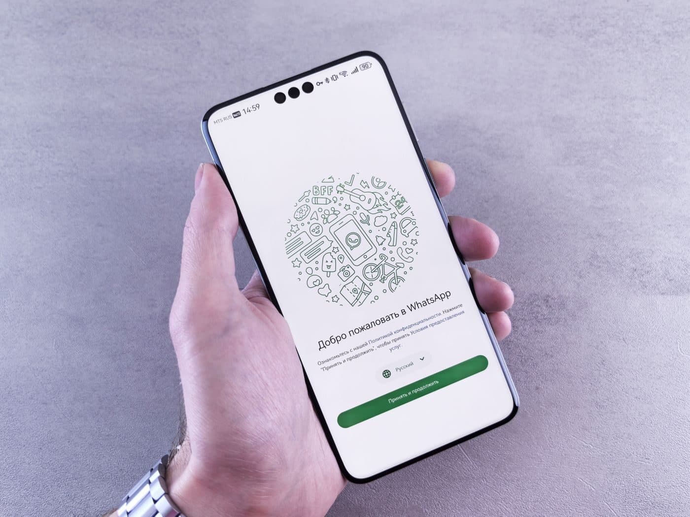 A hand holding a phone showing a WhatsApp welcome screen