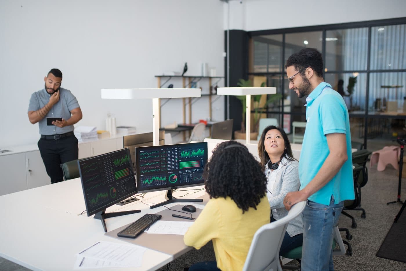 Colleagues collaborating around a laptop and financial data in an office