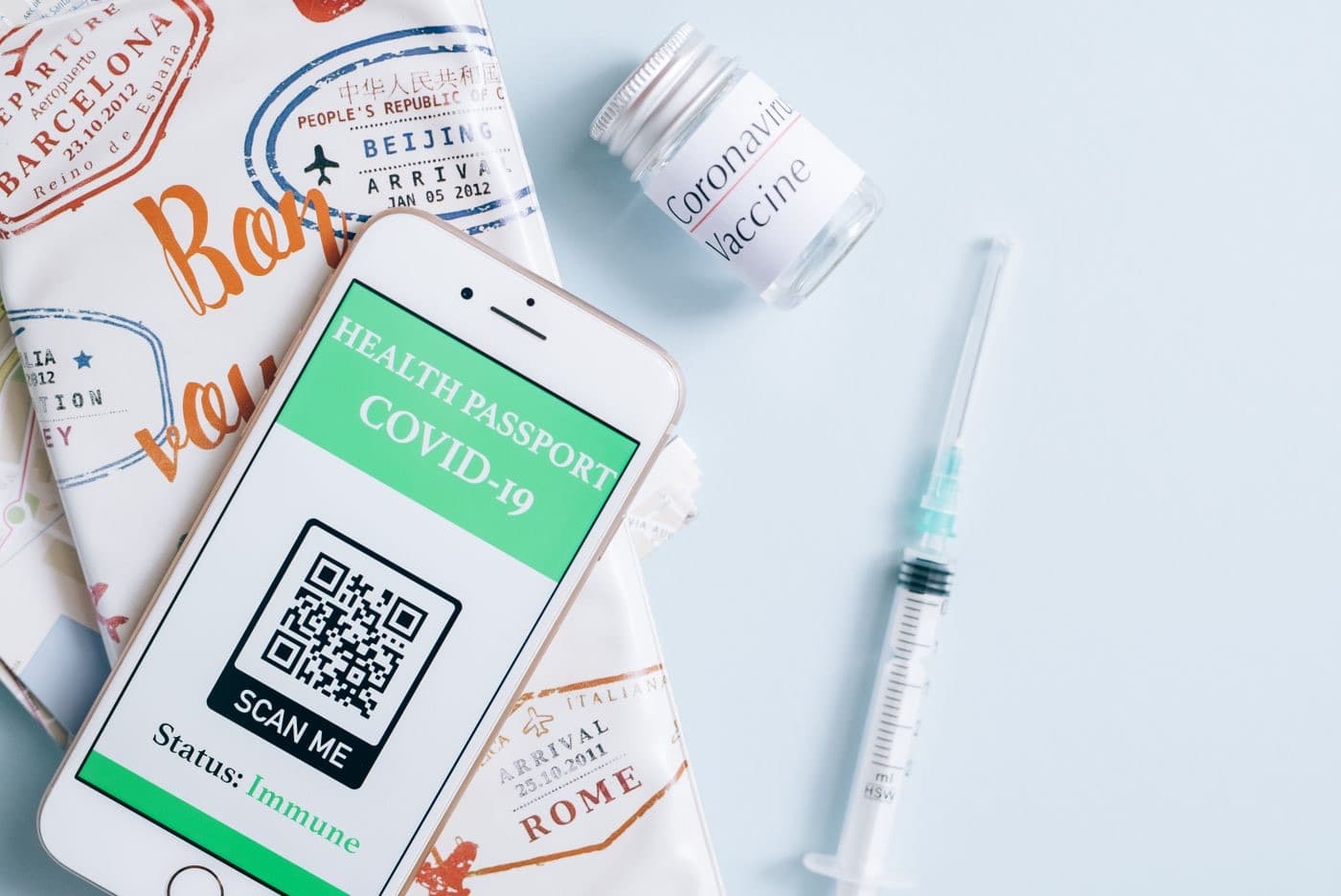 A smartphone displaying a COVID-19 health passport next to a vaccine vial