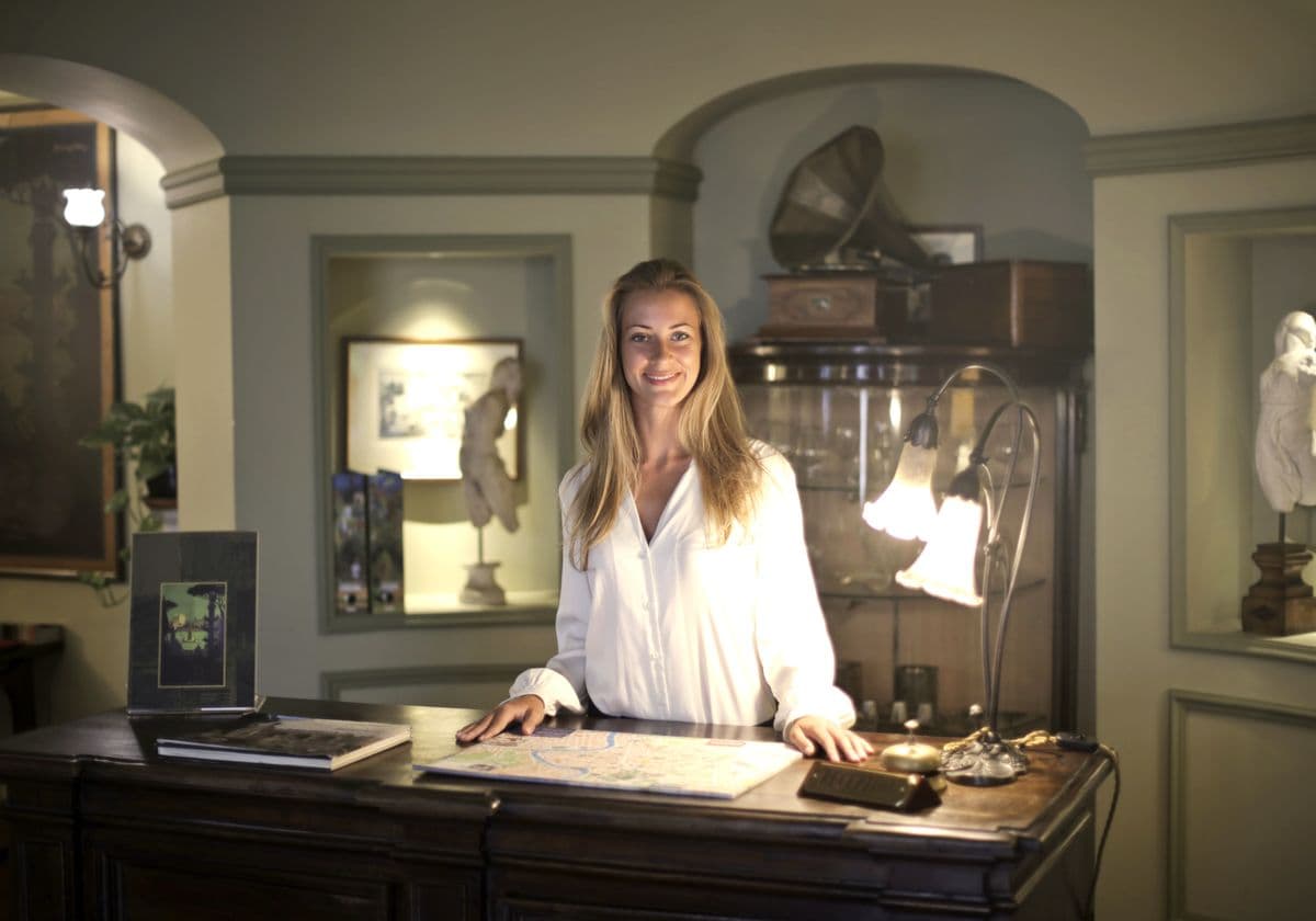 A receptionist welcoming a guest at a hotel desk